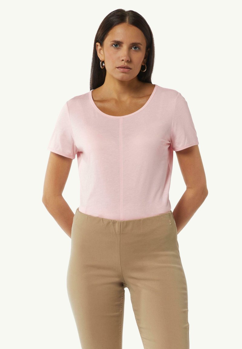 Lichtroze t-shirt met een ronde hals en korte mouwen, gemaakt van zachte stof. Draagt met beige slim-fit broek. Eenvoudig ontwerp, geen patronen.