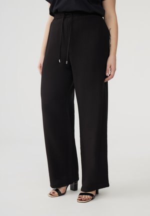 Pantaloni neri a gamba larga con tessuto strutturato, dotati di una vita regolabile con cordoncino e dettagli in metallo argentato.