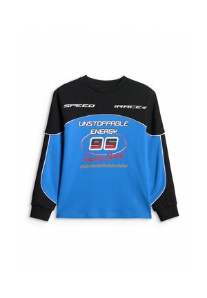 Chłopiec z krótkimi blond włosami, ubrany w czarno-niebieską bluzę z napisem „Unstoppable Energy 95 Racing Speed”, stoi na jednolitym tle.