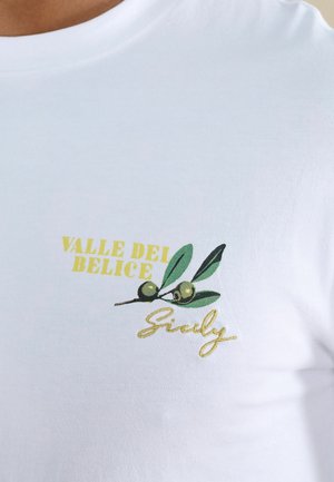 White shirt with yellow text "Valle Dei Belice" and green olive branch illustration above cursive word "Sicily" on chest area.