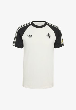 T-shirt blanc avec manches raglan noires, trois bandes blanches sur les épaules, logo de cheval noir brodé et détail de texte jaune.