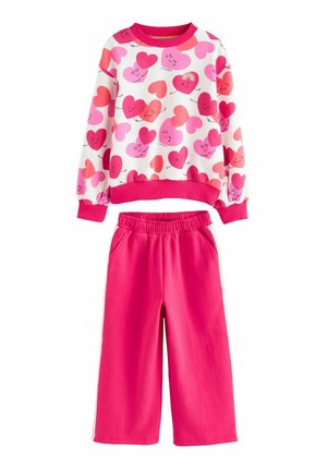 Sweatshirt and sweatpants set. White top with pink heart patterns; ribbed cuffs. Bright pink pants with elastic waistband and side pockets.