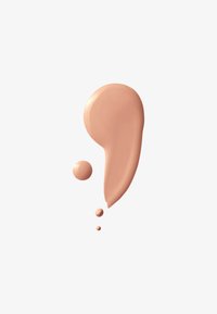 Taches et gouttes de fond de teint liquide beige sur fond blanc, de tailles et formes variées.