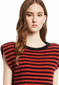 Rood en marineblauw gestreepte gebreide trui met een fuzzy textuur, brede korte mouwen en een ronde halslijn. Lagen van horizontale strepen zichtbaar.