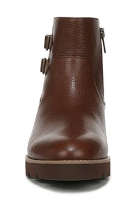 Brown leather ankle boots with a textured finish, two adjustable buckles on the side, and a thick rubber sole.