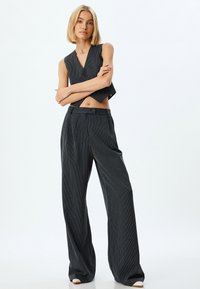 Schwarzes gestreiftes Cropped-Top mit V-Ausschnitt und passenden weiten Hosen. Verfügt über ein elegantes Design mit lockerer Passform und vorderem Knopfverschluss.