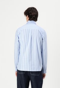 Hellblau gestreiftes Shirt aus Stoff, mit vertikalen Streifen in verschiedenen Breiten, einem geraden Saum und Knopfmanschetten.