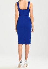 Robe ajustée bleu royal avec un décolleté carré, des bretelles épaisses et une fermeture éclair au dos. Tissu lisse avec une silhouette crayon et une fente arrière.