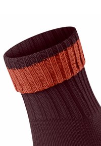 Chaussette tricotée avec un design en côtes, corps marron foncé et revers orange contrastant. La texture est douce avec une apparence robuste.