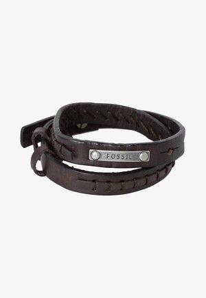 Mørkebrunt læderarmbånd med syninger og en metalplade med indgraveret mærkenavn Fossil, snoet på en hvid baggrund.