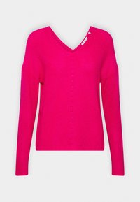 Svetr s výstřihem do V v jasně růžové barvě, s ribkovanou texturou, dlouhými rukávy a mírně otevřenými rameny. Uprostřed jsou malé dekorační otvory.