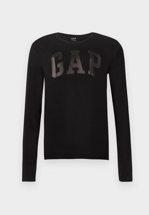Μαύρο μπλουζάκι με μακριά μανίκια και στρογγυλή λαιμόκοψη, με τη λέξη "GAP" τυπωμένη σε μεγάλα, λαμπερά μαύρα γράμματα στο στήθος, απλό φόντο.