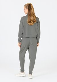 Grijze cropped sweatshirt en bijpassende joggers van zachte stof, met een ontspannen pasvorm en elastische manchetten, gecombineerd met lichte sneakers.