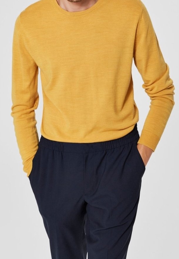 Mosterdgele, trui met ronde hals in een gestructureerde brei, gecombineerd met donkerblauwe, broek met elastische taille en zijzakken.