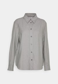 Camicia grigia a maniche lunghe con colletto a punta, caratterizzata da una texture liscia e bottoni scuri a contrasto lungo la parte anteriore.