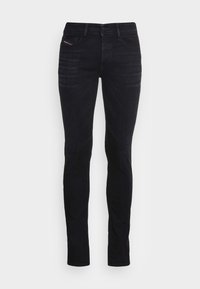 Jeans de mezclilla negra con corte ajustado, que cuentan con cinco bolsillos, un ligero desgaste en la tela y una cintura de altura media. Costuras visibles que realzan el diseño.