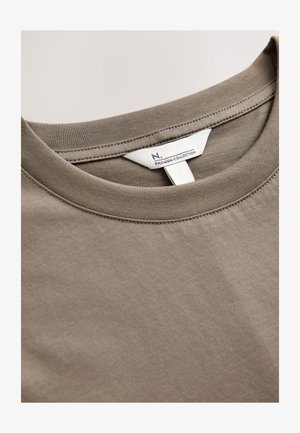 Brun bomulds T-shirt med rund hals og en glat tekstur. Indeholder en vaskeanvisning trykt på en hvid mærkat indeni kraven.