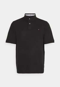 Černé polo tričko z hladké látky, s límcem na dva knoflíky a malým vyšitým logem na hrudi. Krátké rukávy.