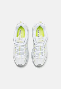 Weiße Sportschuhe mit grauen Akzenten, Obermaterial aus Netzgewebe und gelb-grünen Details. Verfügt über ein Schnürdesign und eine gepolsterte Innensohle für zusätzlichen Komfort.