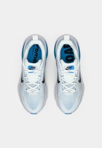 Une paire de chaussures de course blanches et bleues avec des logos de swoosh noirs et des étiquettes "RUN" sur les languettes, vue d'en haut sur un fond blanc.