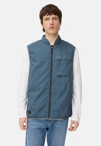 Lyseblå ærmeløs vest med høj krave, lynlås foran og brystlomme; lavet af glat, letvægtsstof.