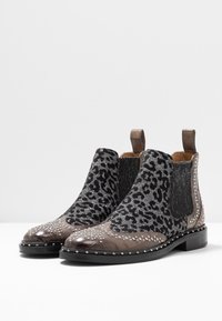 Botines Chelsea hasta el tobillo con estampado de leopardo negro texturizado y acentos brillantes, detalles de tachuelas plateadas y diseño de punta afilada.