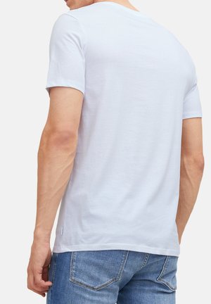 Weißes T-Shirt mit kurzen Ärmeln aus Baumwolle, mit rundem Ausschnitt und normaler Passform, von hinten mit hellblauen Jeans gesehen.
