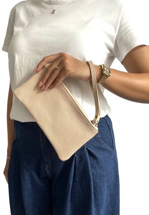 Clutch in pelle beige texturizzata con un cinturino da polso, tenuto in mano, dotato di chiusura zip e design minimalista, adatto per un uso casual.