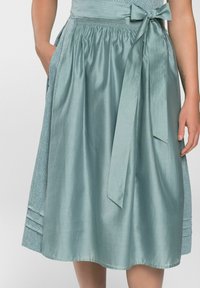 Een teal, knie-lange rok van gladde stof met een strik in de taille, voorzien van zijzakken en een gestructureerd detail langs de zoom.