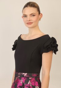Czarna sukienka z krótkimi falbaniastymi rękawami i plisowanym dołem, zdobiona intensywnym kwiatowym wzorem w odcieniach różu i fioletu.