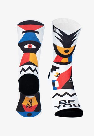 Bunte gemusterte Socken mit abstrakten Designs in Rot, Blau, Gelb und Schwarz, auf einem weißen Grund mit schwarzen Akzenten an der Zehe.