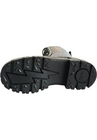 Suela de zapato de goma negra con un patrón de zigzag. Presenta profundos surcos para agarre y un logo circular. La parte superior muestra un diseño textil multicolor.