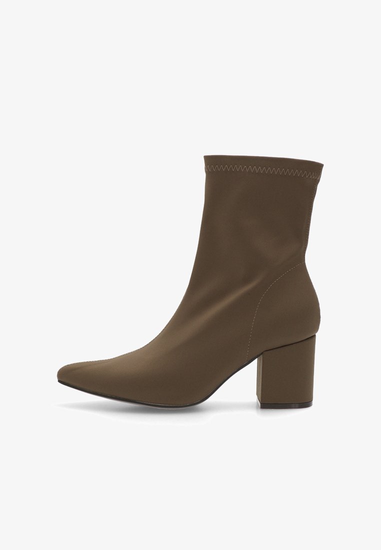 Botín marrón de tobillo hecho de tela suave con punta afilada y tacón medio de bloque. Presenta costuras visibles en la parte superior.
