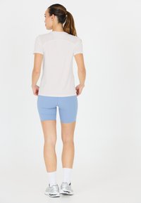 Let, let, let og let træningstrøje i hvidt med korte ærmer, parret med himmelblå tætsiddende shorts. Har et strømlinet design og åndbart materiale.