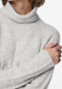 Jasnoszary, prążkowany golf o luźnym kroju i długich rękawach. Charakteryzuje się miękką teksturą oraz delikatnymi poziomymi paskami.