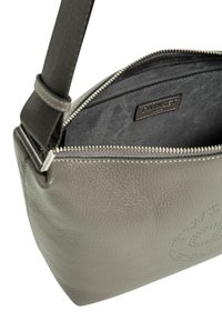 Borsa in pelle grigia con superficie testurizzata, chiusura con zip e interno caratterizzato da un'etichetta di marca. Tracolla regolabile e dettagli di cucitura discreti.