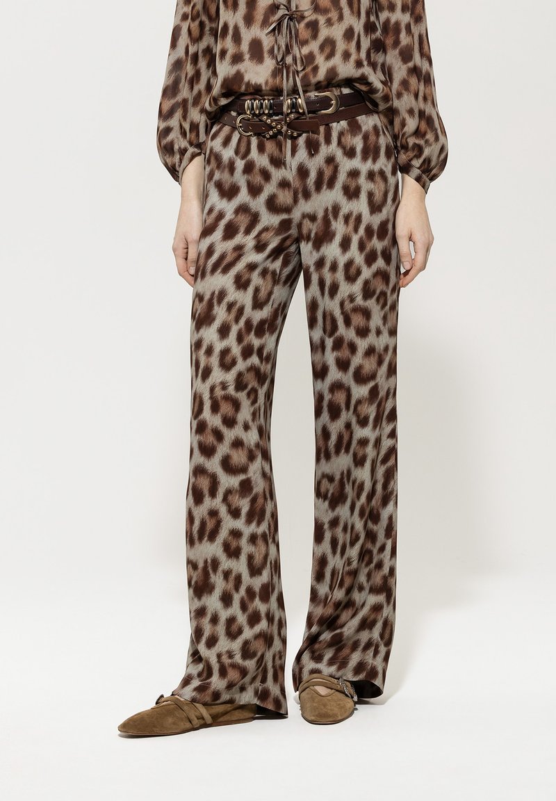 Leopard-print trousers with a loose fit, made of soft fabric, featuring brown and beige tones, paired with a brown belt and flat shoes.