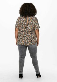 Blommig blus med korta ärmar, svart bakgrund, färgglada blommor, nyckelhål på ryggen; kombinerad med grå skinny jeans och svarta klackar.