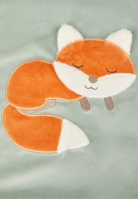 Orangenes Fuchsdesign auf weichem mintgrünem Stoff, mit strukturiertem Fell, weißen Akzenten an Ohren und Schwanz sowie minimalistischen, gestickten Gesichtszügen.
