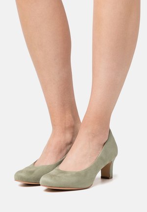 Escarpins en daim vert à talons hauts avec un bout arrondi et un talon bloc moyen, présentant une texture lisse et un design classique.