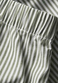 Tissu rayé vert et blanc avec une taille élastique froncée, présentant une texture lisse et un motif vertical uniforme.