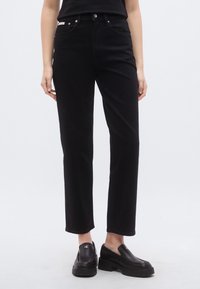 Μαύρο τζιν ψηλόμεσο με ίσια γραμμή, κατασκευασμένο από denim, με πέντε τσέπες, κλείσιμο με κουμπί και μπροστινό φερμουάρ. Χωρίς ορατά σχέδια.