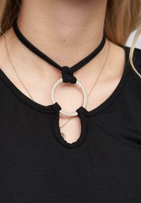 Zwarte choker ketting met een geknoopt stoffen band en een ronde metalen hanger. Bevat een sleutelgatopening bij de halslijn.