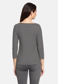 Schwarz-weiße gestreifte Dreiviertelärmelbluse aus weichem Stoff, mit Boot-Ausschnitt und figurbetonendem Design.