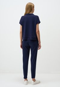 Navy loungewear set met een kortärmige top met een subtiele kraag en bijpassende afgezwakte broek. Zachte stof met een gladde textuur.