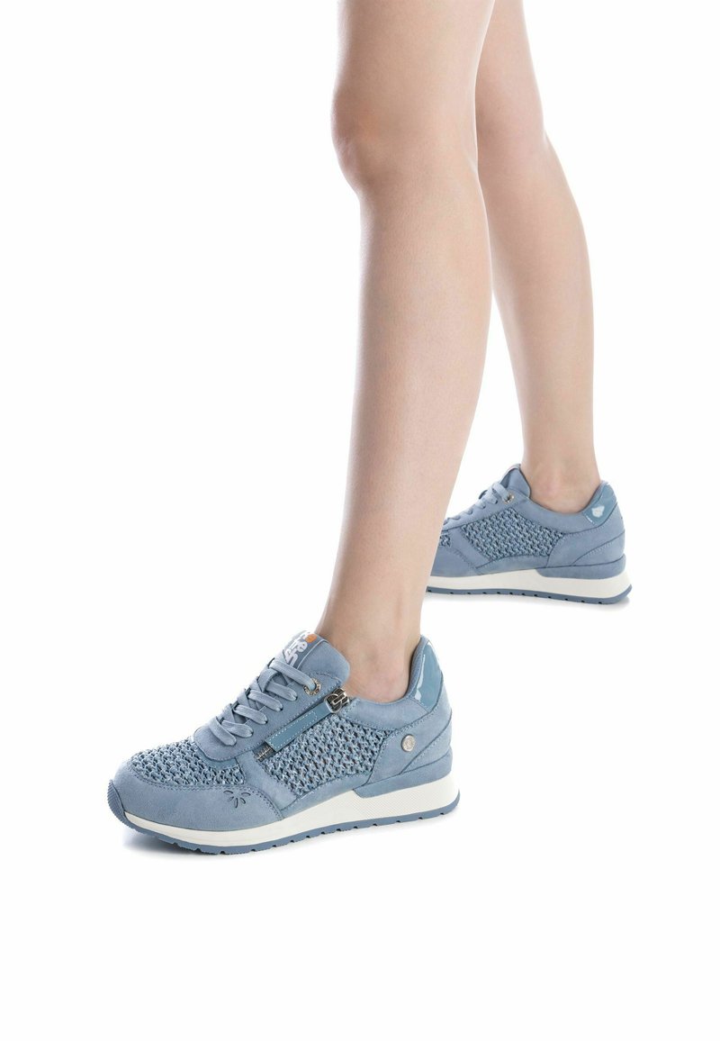 Zapatillas deportivas de color azul claro con un diseño de malla tejido, acentos de ante suave, cierre con cordones y un detalle de cremallera en el lateral.