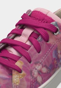 Baskets roses avec des lacets rose vif et un motif de papillon sur le tissu près des œillets en métal et des détails cousus.