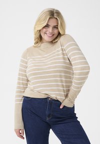 Beige long-sleeve top with horizontal white stripes, crew neckline, soft texture; paired with dark blue jeans featuring visible stitching.
