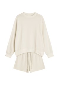 Zestaw odzieży loungewear z dzianiny waffle w kolorze off-white, składający się z długiego rękawa z okrągłym dekoltem i luźnym krojem oraz szortów ze sznurkiem.