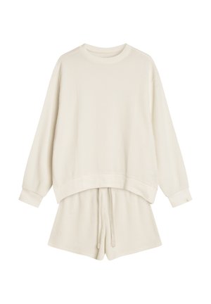 Zestaw odzieży loungewear z dzianiny waffle w kolorze off-white, składający się z długiego rękawa z okrągłym dekoltem i luźnym krojem oraz szortów ze sznurkiem.
